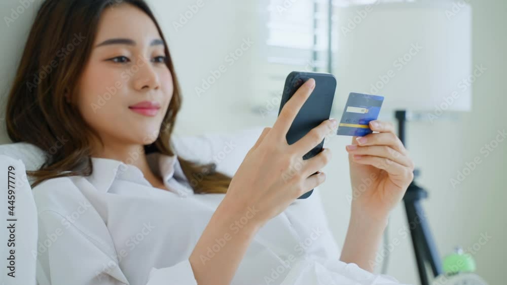 Asian attractive woman enjoy shopping online on bed at home in morning