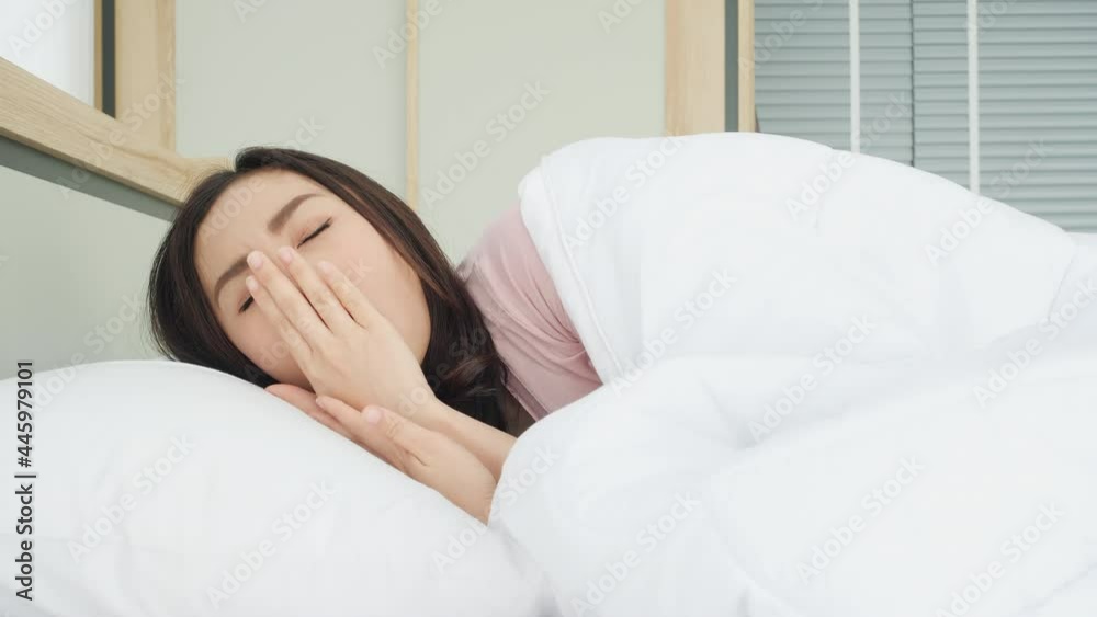 Asian beautiful woman waking up in the morning at home. Young girl stretches and gets up from bed in bedroom at home. Concept of lifestyle, vacation and healthy. Asian beautiful woman waking up in the morning at home. Young girl stretches and gets up from bed in bedroom at home. Concept of lifestyle, vacation and healthy.