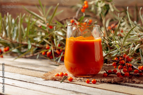 A glass of sea buckthorn juice with fresh berries on an old wooden table. Healthy and diet food.