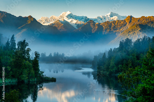 Mist at dawn preventing the reflections of the snow capped southern alps on the calm water at Lake Matheson