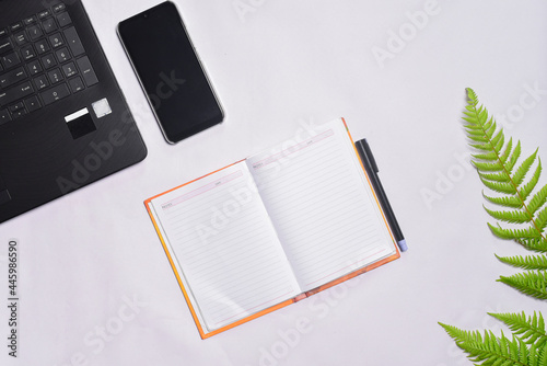 Office desk with laptop, phone, notebook and pen