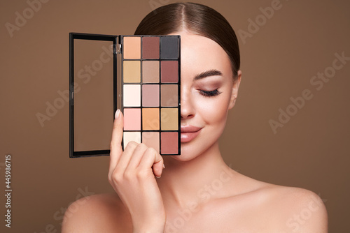 Beauty woman with eye shadow makeup palette. Model with healthy perfect skin, close up portrait. Cosmetology, beauty and spa photo