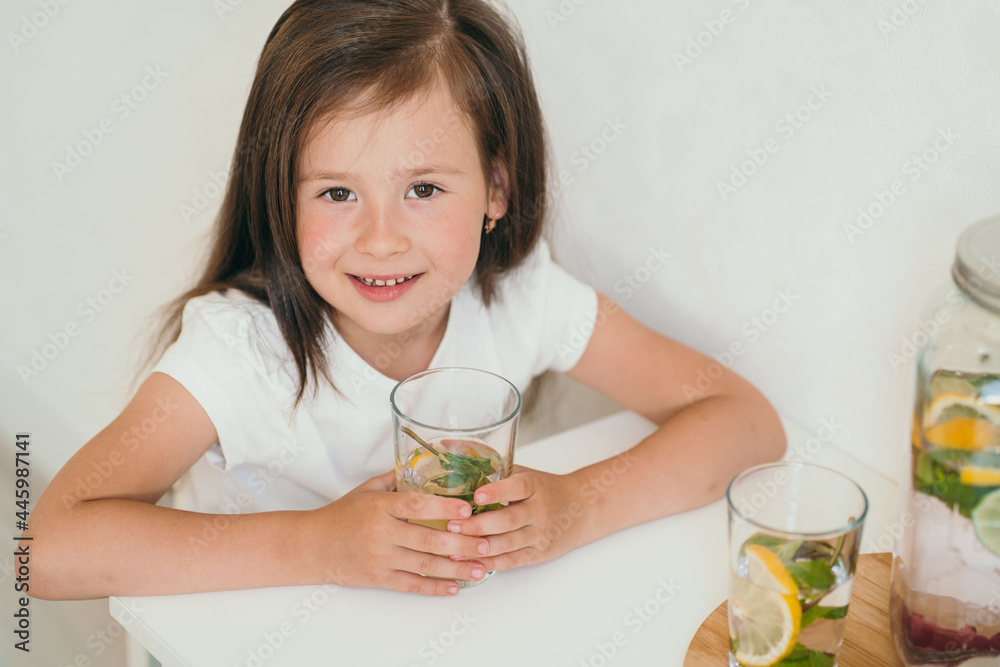 A cute kid drinks homemade lemonade. Healthy lemonade with lemon and lime. Summer cooling drink for children. A cute kid drinks homemade lemonade. Healthy lemonade with lemon and lime. Summer cooling drink for children.