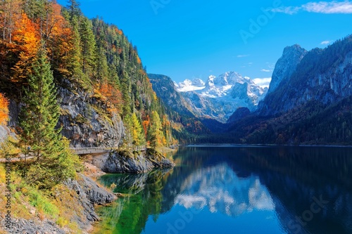 Fototapeta Naklejka Na Ścianę i Meble -  Beautiful autumn scenery of Lake Gosausee with snow-capped Dachstein Mountain in the background and reflections on the smooth water, in Gosau, Austria. A dramatic unusual scene of Alps, Europe.