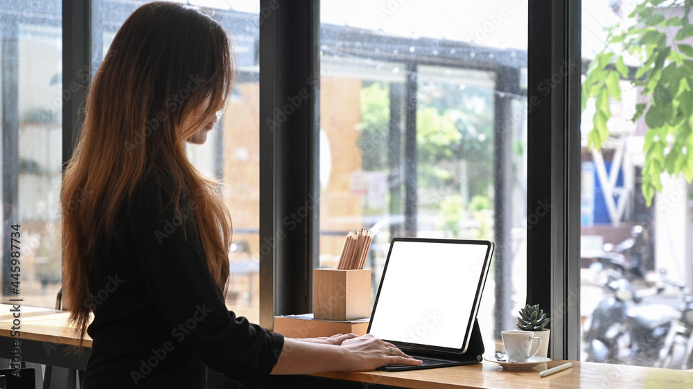 Side view of beautiful Asian woman working with laptop at cafe. Side view of beautiful Asian woman working with laptop at cafe.