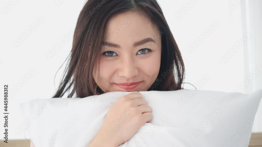 Asian beautiful woman happy expression and looking at camera in bedroom. Teenage girl sitting on bed and happy smile with conference internet while being quarantine at home. Asian beautiful woman happy expression and looking at camera in bedroom. Teenage girl sitting on bed and happy smile with conference internet while being quarantine at home.