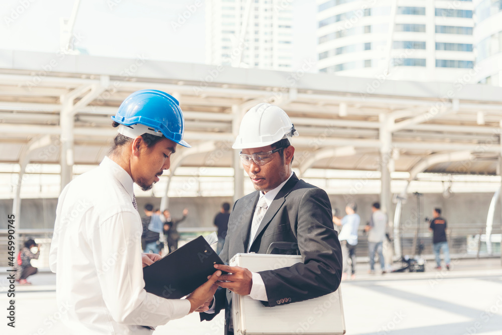 Civil engineer teams meeting working together wear worker helmets hardhat on construction site in modern city. Foreman industry project manager engineer teamwork. Asian industry professional team