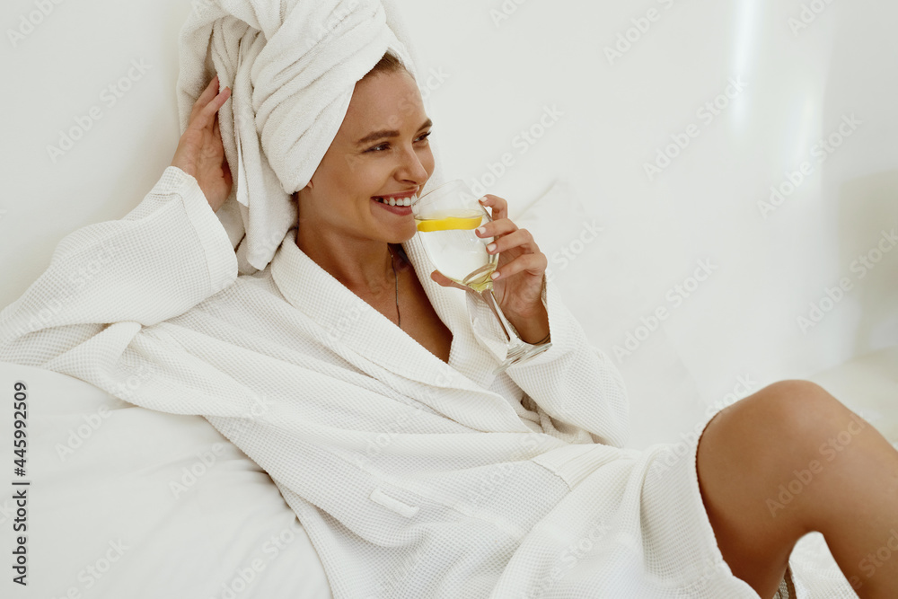 Smiling girl in bathrobe drink lemonade from glass - obrazy, fototapety, plakaty 