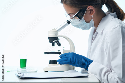 woman scientist looking through a microscope research biology diagnostics