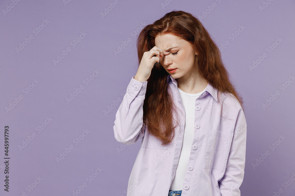 Sad tired young redhead curly woman 20s wear white T-shirt violet jacket keep eyes closed rub put hand on nose isolated on pastel purple color wall background studio portrait. People emotions concept Sad tired young redhead curly woman 20s wear white T-shirt violet jacket keep eyes closed rub put hand on nose isolated on pastel purple color wall background studio portrait. People emotions concept