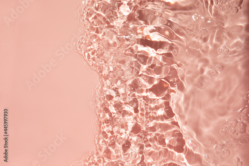 Pink liquid colored clear water surface texture with splashes bubbles.
Summer banner background.Trendy  nature background. Transparent clear  water.

