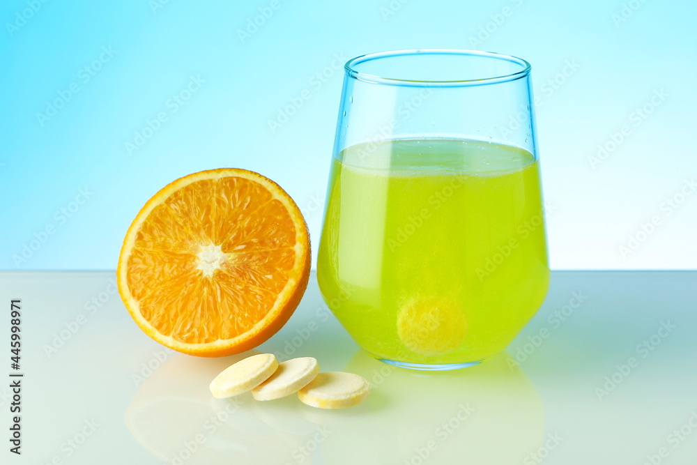 effervescent vitamin C tablet dissolves in water. a glass of water