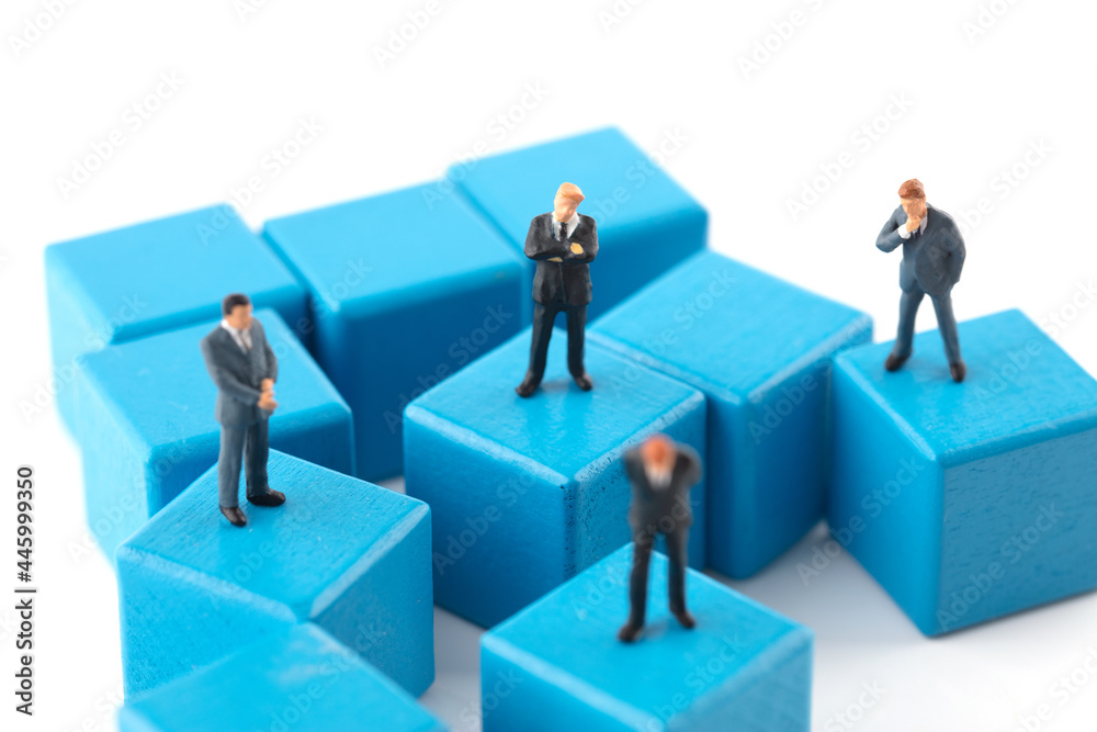 Miniature businessman standing on small square