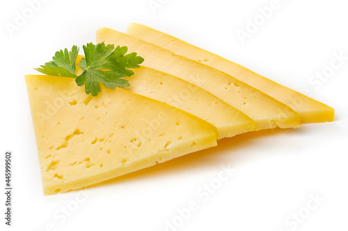 Pieces of semi-hard or hard yellow cheese with holes and parsley leaf isolated on a white background.