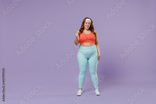 Full length young fun chubby overweight plus size big fat fit woman wear red top warm up training show thumb up gesture isolated on purple background studio home gym. Workout sport motivation concept.