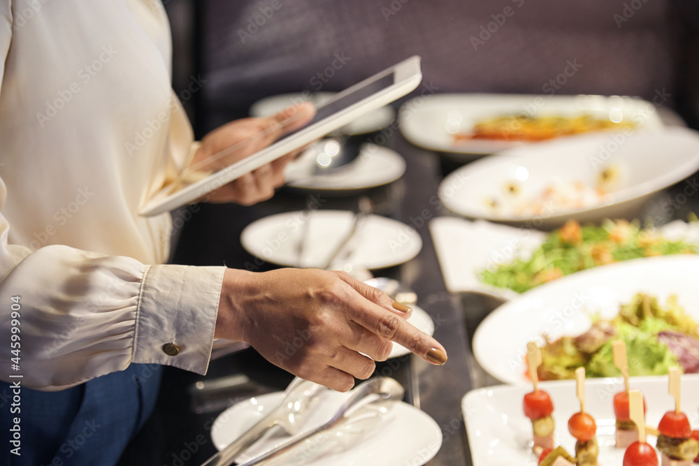 Hands of female restaurant owner checking plates with food ready for serving