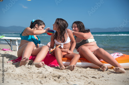 Group of young female teenagers playing with a colourful game on the beach. Holiday and friendship concept.