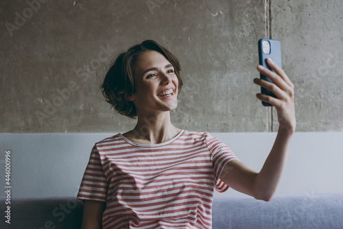 Cropped up photo shot young in casual clothes sitting on grey sofa doing selfie shot on mobile cell phone post photo on social network rest relax indoors flat at home People lifestyle leisure concept.