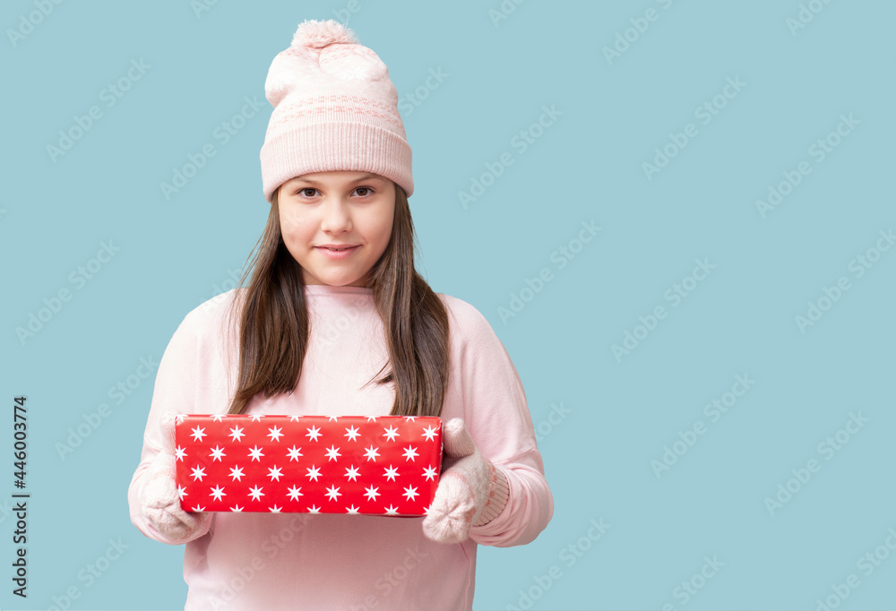 smiling girl in a pink knitted sweater and knitted hat and mittens, holds boxes with gifts smiling girl in a pink knitted sweater and knitted hat and mittens, holds boxes with gifts