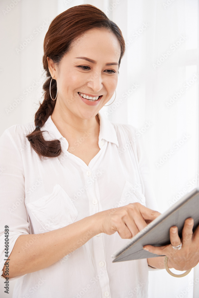 Portrait of pretty smiling senior woman using mobile application on tablet computer, answering messages on shopping online Portrait of pretty smiling senior woman using mobile application on tablet computer, answering messages on shopping online