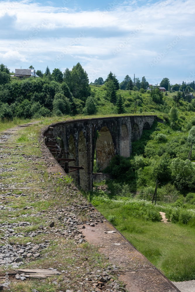 Old viaduct in Vorokhta, Carpathians. View from the bridge to the bend and the columns below surrounded by lush greenery