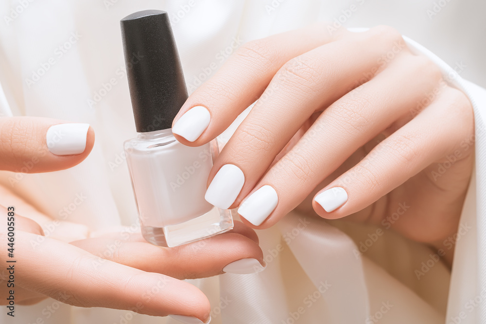 Female hands with white nail design. White nail polish manicure. Woman  hands hold nail polish bottle on white fabric. Stock Photo | Adobe Stock