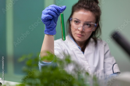 Chemist researcher woman holding test tube with dna liquid observing genetic mutation on sample researching for biochemistry expertise. Scientist biologist working in agriculture laboratory. photo