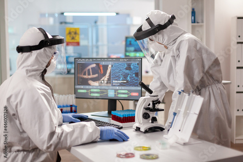 Scientists in protection suits analysing dna sample infected with virus. Team doctors working with various bacteria, tissue and blood samples, pharmaceutical research for antibiotics