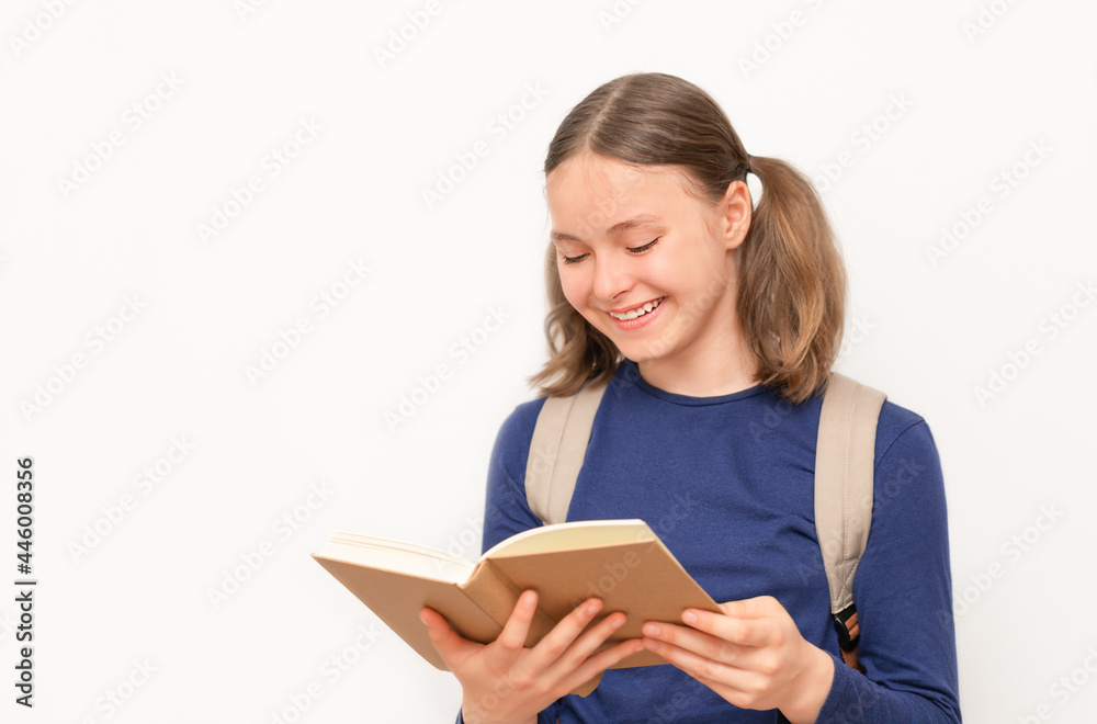 Smiling schoolgirl looking at the open textbook on the gray surface Smiling schoolgirl looking at the open textbook on the gray surface