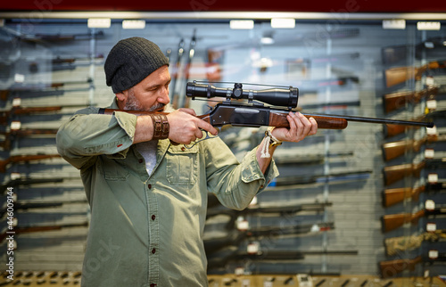 Hunter buying rifle with optical sight, gun store