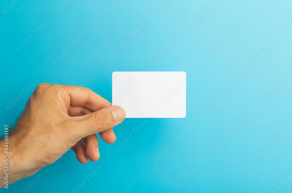Empty plastic card in hand on colored background. ID or credit money card isolate Empty plastic card in hand on colored background. ID or credit money card isolate