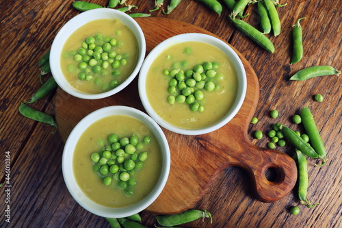 Fresh green pea soup with pea seeds and pea pods around . Selective Focus, Focus on the pea in the middle of the soup