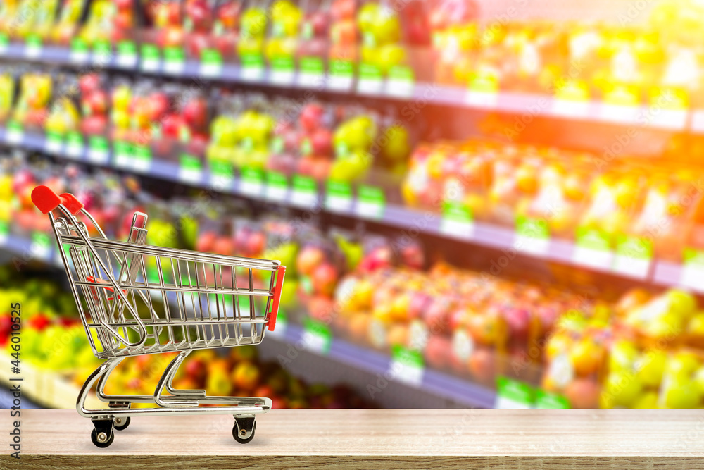 Supermarket grocery table background with cart. Food and groceries blurred on store shelves. Supermarket grocery table background with cart. Food and groceries blurred on store shelves.