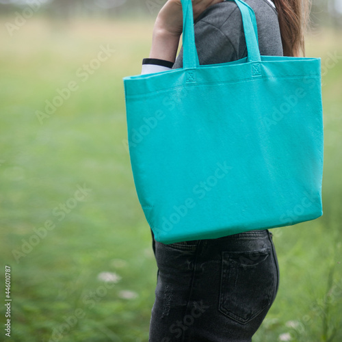 Woman holding emerald green tote bag, outdoor photo