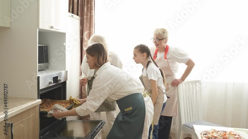 Wallpaper Mural Young woman, grandmothers and daughter take out a pizza from an electric oven. the best experience in cooking is making food meal with family, adults teach child to cook, in kitchen at day time Torontodigital.ca