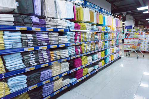 Stacked of colorful towels displaying on the shelves in a supermarket. Fluffy bath towels piles in a shop