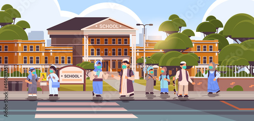 arabic schoolchildren wearing masks to prevent coronavirus pandemic pupils standing together near school building