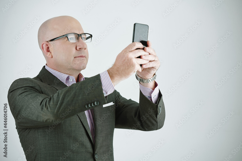 Mature businessman in suit making photo on his mobile phone isolated on white background Mature businessman in suit making photo on his mobile phone isolated on white background