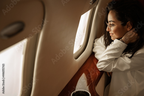 Foto Businesswoman brunette with glasses in a white jacket flies in a charter busines