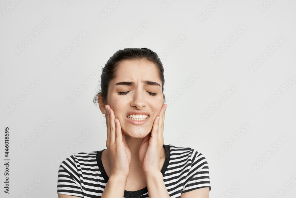 woman in striped t-shirt holding face dentistry discomfort pain woman in striped t-shirt holding face dentistry discomfort pain