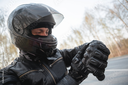 Motorbiker is checking the time on his wrist watch. © Dmitriy