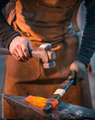 Blacksmith forges a red-hot metal blank. Unrecognizable person.