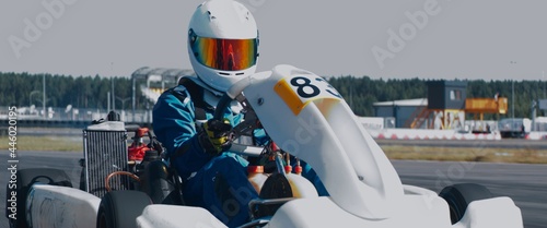 Photo Front view of teenager professional racer driving his go kart on a race track