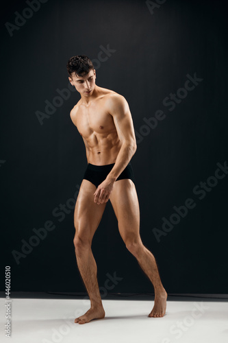 man in black panties with naked muscular body dark background