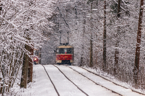 An old tram moving through a winter forest