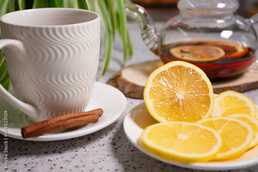 A hot tea drink with lemon and orange, a teapot and a white cup, served with delicious lemon and cinnamon. Fragrant and warming tea. Step 5