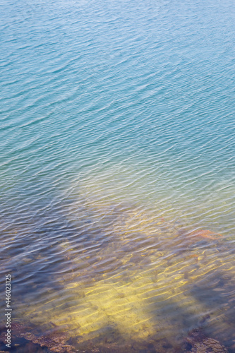 Clear azure water of a lake on a sunny day. Visible shore under water.