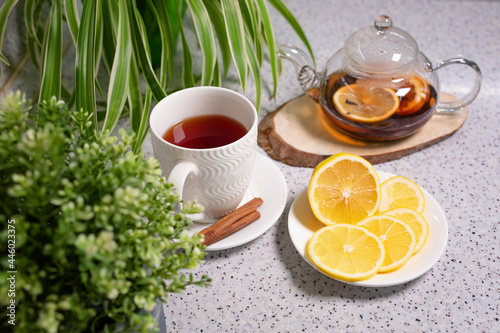 A hot tea drink with lemon and orange, a teapot and a white cup, served with delicious lemon and cinnamon. Fragrant and warming tea. Step 6