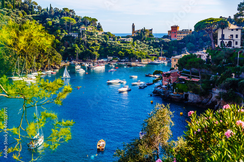 Fototapeta Naklejka Na Ścianę i Meble -  Fishing boats moored on water in harbor of Ligurian and Mediterranean Sea near coastline of Riviera di Levante of National park Cinque Terre Coast with blue sky, Riomaggiore village, Liguria, Italy.
