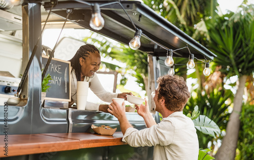 Afro food truck owner serving meal to male customer - Modern business and take away concept